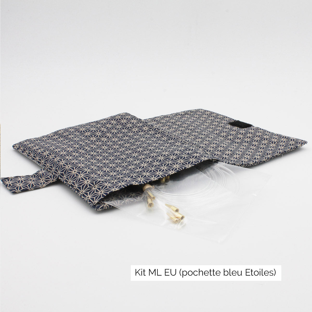 Présentation de la pochette du kit Seeknit ML EU de Kinki Amibari, en tissu bleu marine avec étoiles japonisantes, ouverte à plat, avec des câbles qui dépassent sur le côté