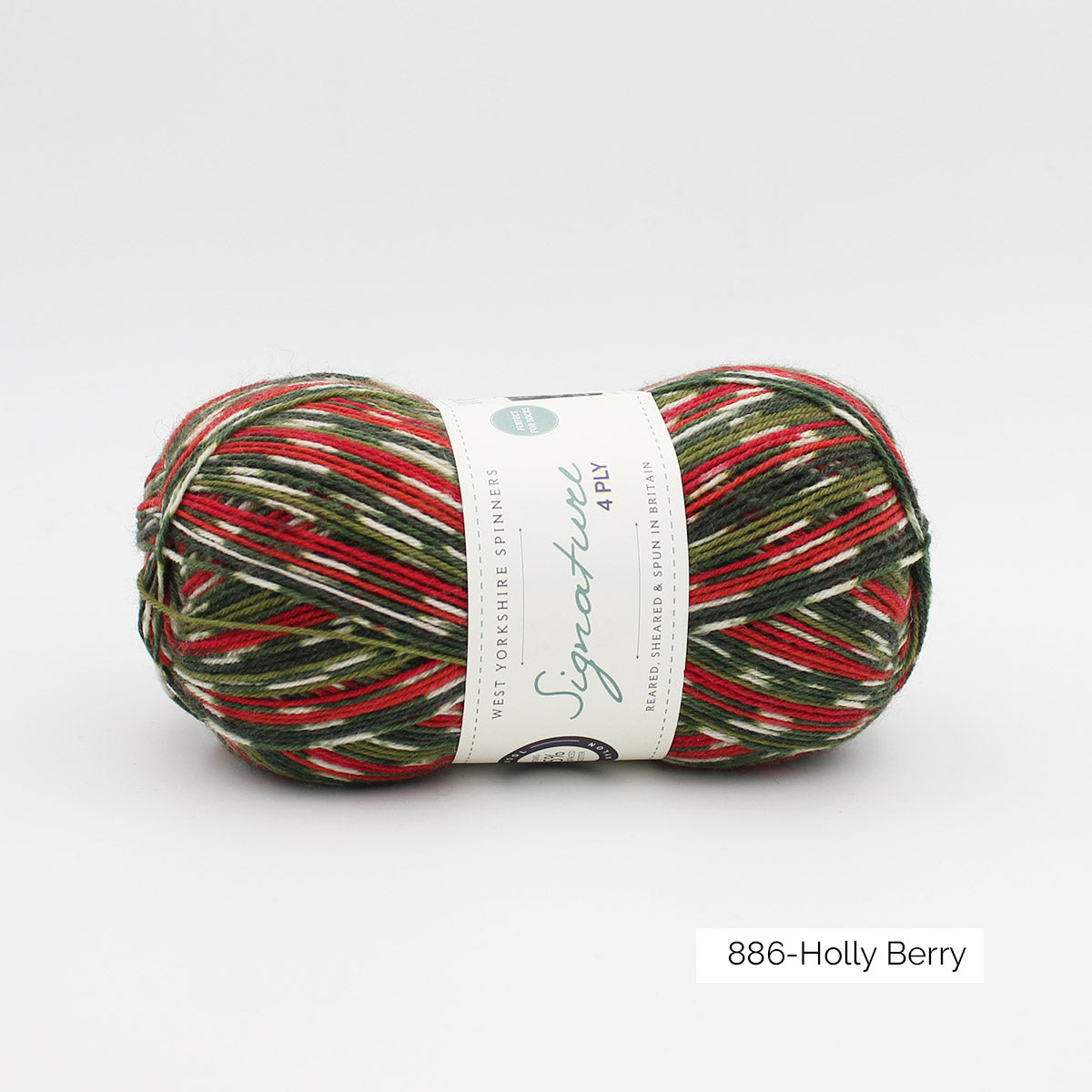 Une pelote de laine à chaussettes de la collection spéciale de Noël 2020 de West Yorkshire Spinners, coloris Holly Berry (création d'un motif dans les tons blanc, vert mousse et sapin et rouge)